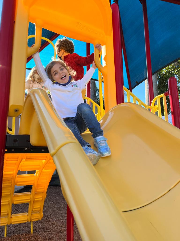 Toddler in Jeans and White T-Shirt sliding on a yellow slide